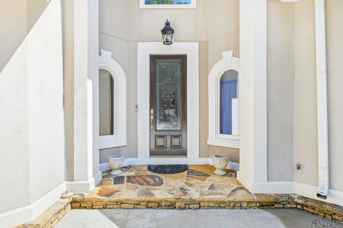 Covered front entry with columns, stone threshold, and a wood door