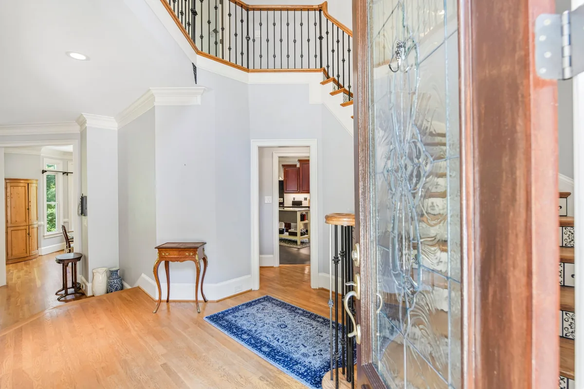 Interior hall with hardwood floors, white staircase, and front doorway